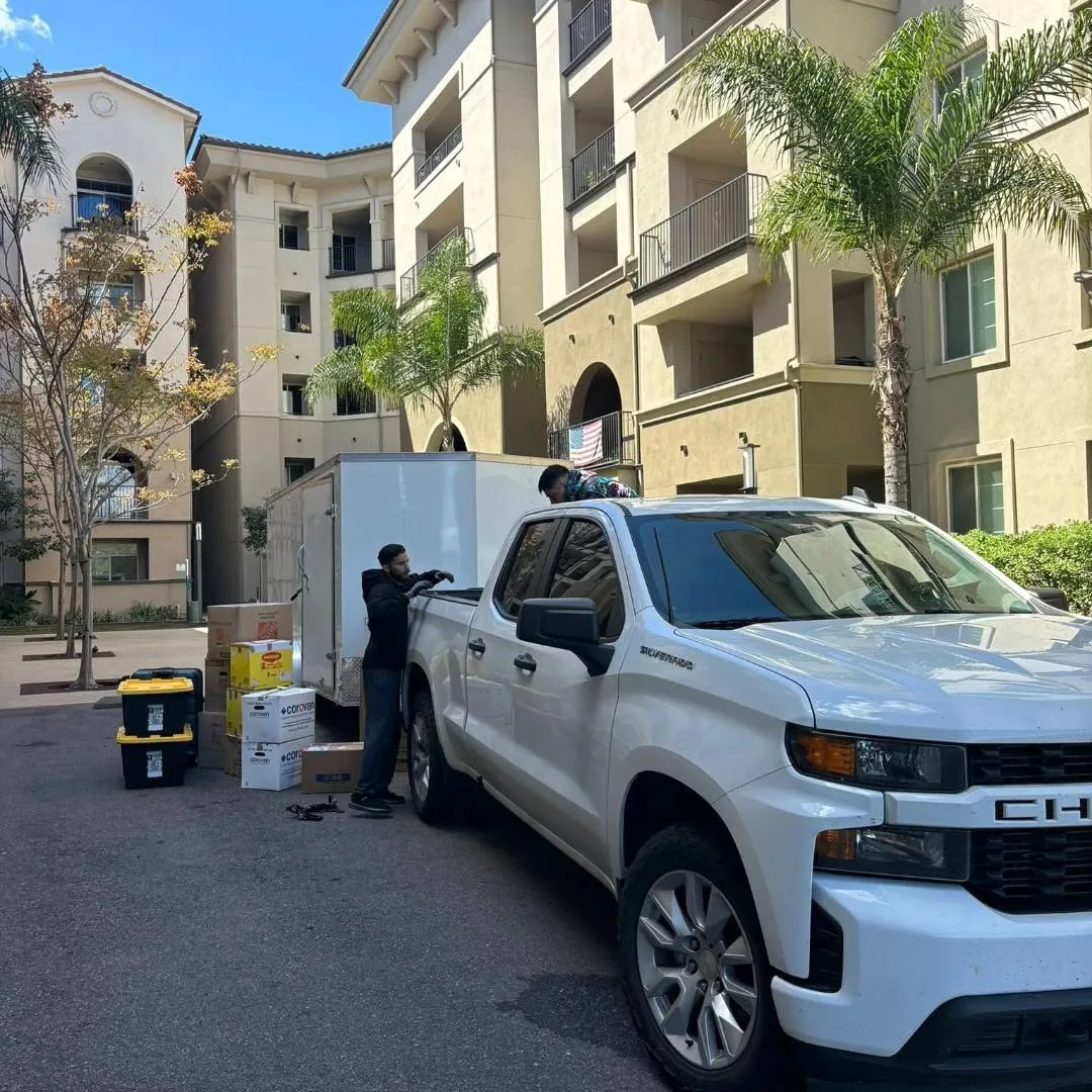 Jesse loading boxes into the JS trailer outside an apartment building